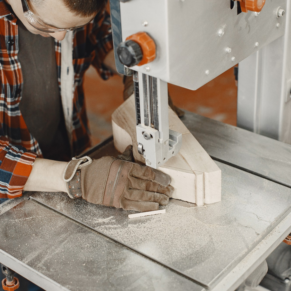 Professional woodworker cutting timber using a bandsaw during custom carpentry work
