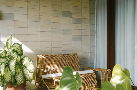 Outdoor patio with modern wall tiles and rattan seating surrounded by greenery